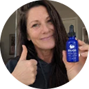 A woman giving a thumbs-up while holding sleepwhale bottle with a dropper in a circular portrait frame.